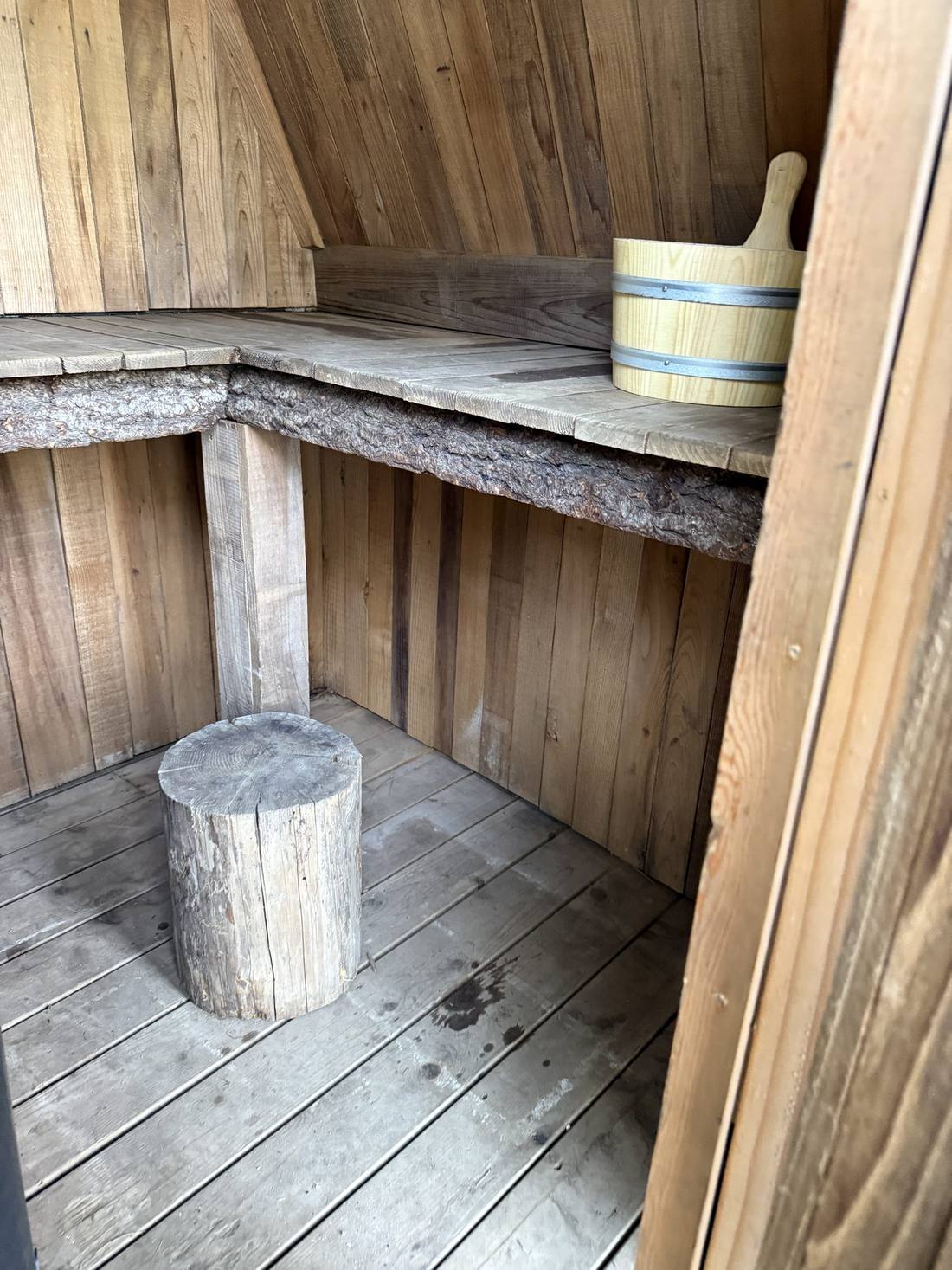 Inside Big Red — weathered cedar, a bucket and a log stool