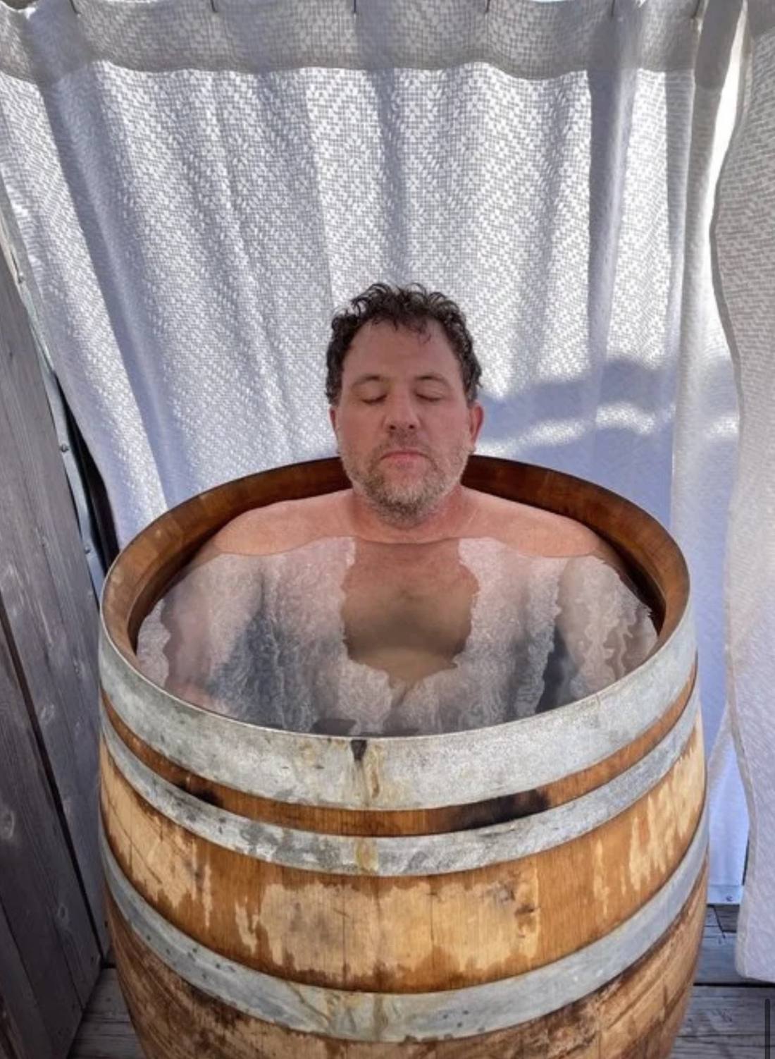 Kenny up to his shoulders in a wine barrel of ice water
