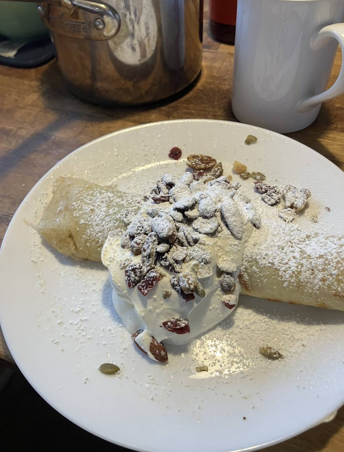 A crepe with whipped cream, toasted almonds and powdered sugar