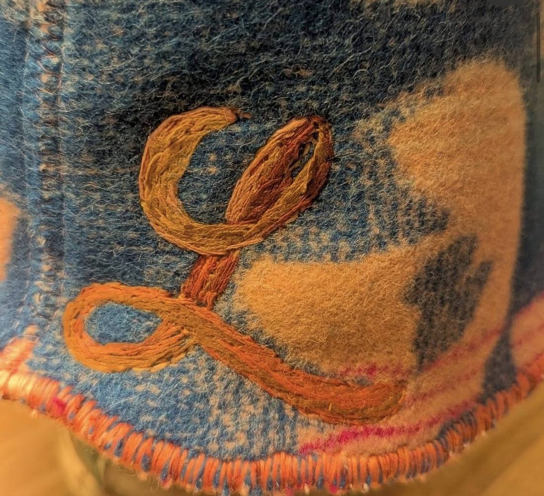 Close-up of hand embroidery on the brim of a wool hat