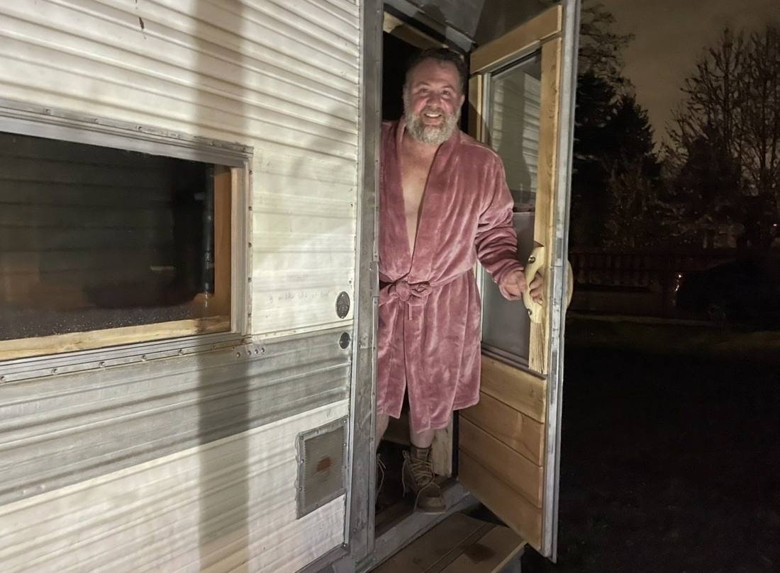 Kenny in a robe in the doorway of the sauna at night