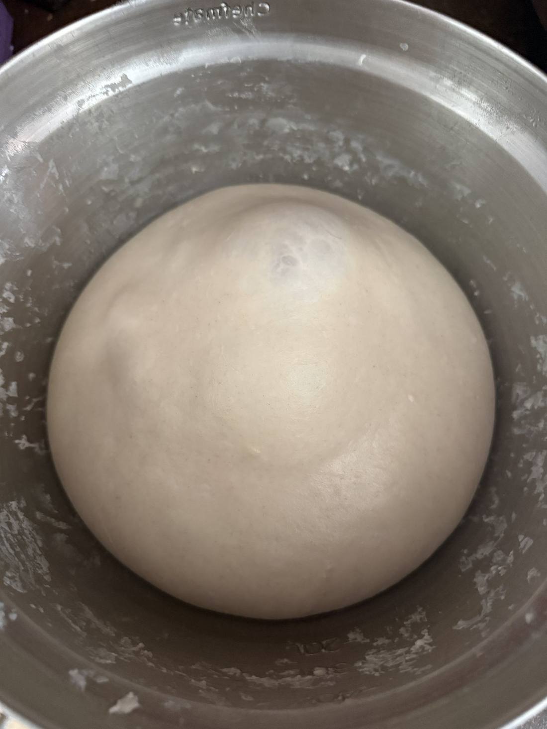Pizza dough proofing in a metal bowl